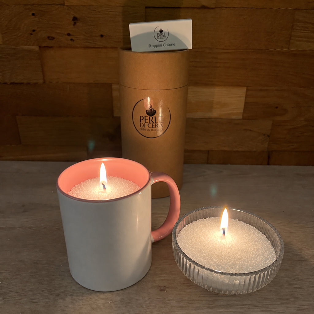Candele di Perle di Cera accese in una tazza e in una ciotola di vetro, accanto al Kit Essenziale